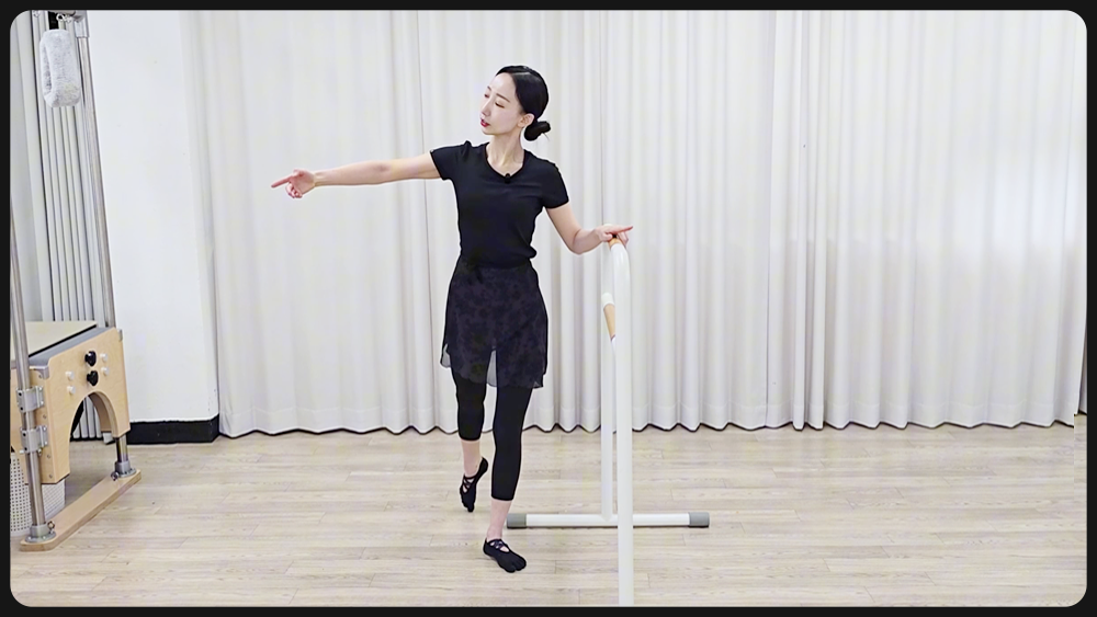 발레바를 잡고 플리에 동작을 시연하는 장면